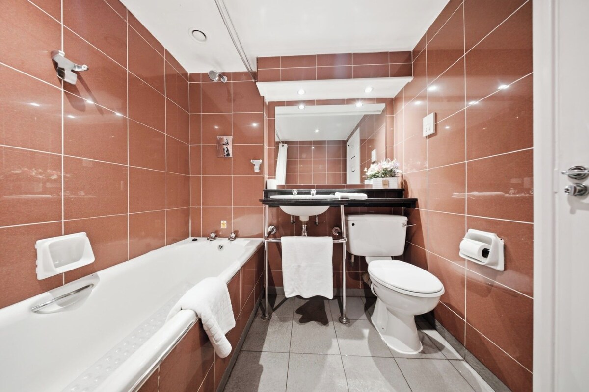 A bathroom with a bathtub, toilet, sink, and mirror.