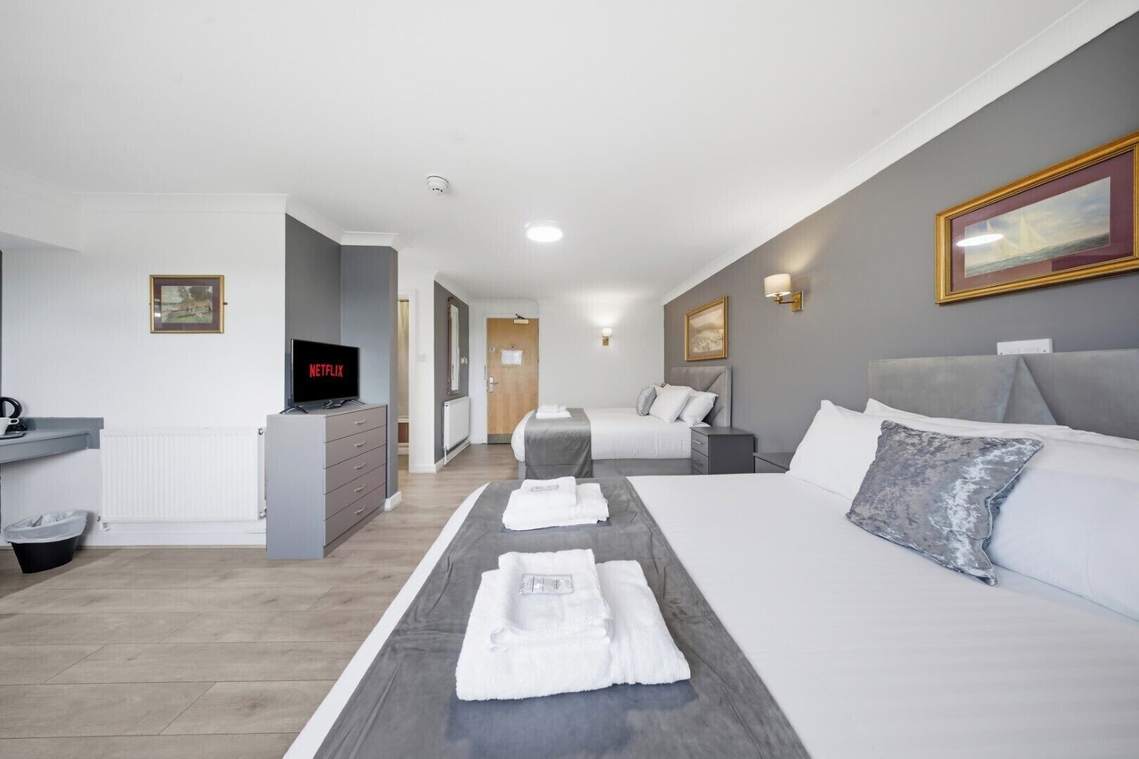 A hotel room with a bed, a desk with a TV, a dresser, and a bathroom.