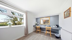 Un baño con ventana, dos sillas de madera, un espejo y un radiador.