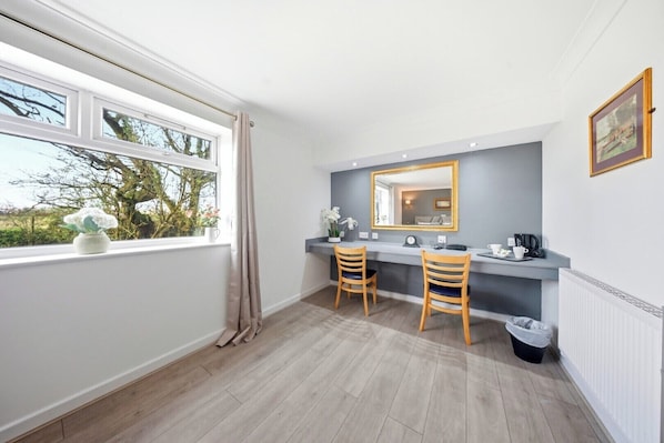 Un baño con ventana, dos sillas de madera, un espejo y un radiador.