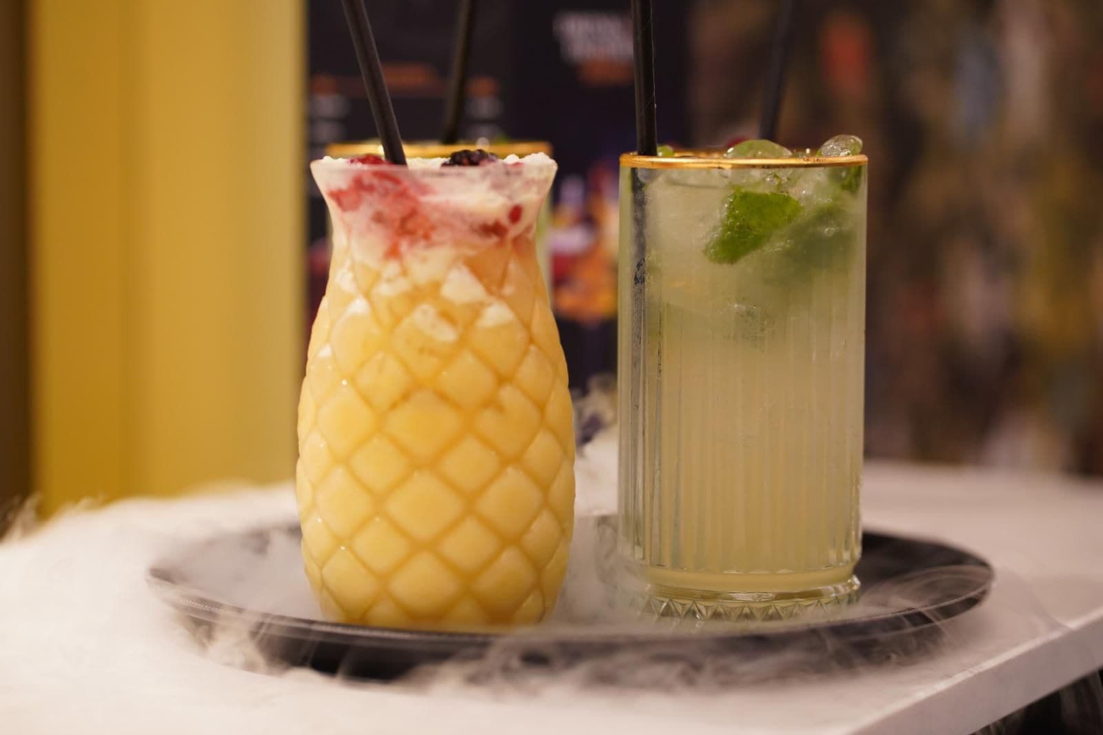 Two drinks on a tray, one in a glass and one in a bottle, with a blurred background.