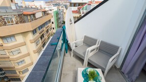 Un balcon avec un coin salon, une petite table agrémentée d’une plante, et une vue sur le paysage urbain.
