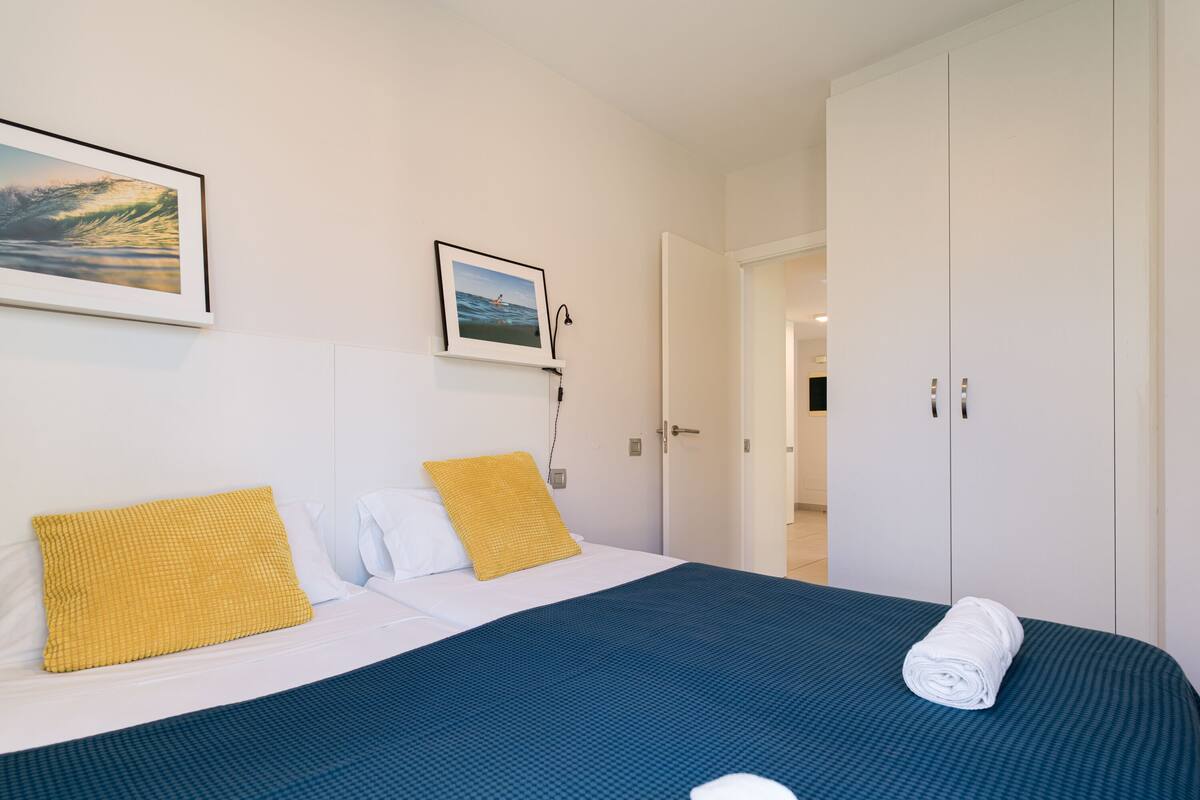 Quarto de hotel com cama, uma janela grande e porta que dá para um banheiro.