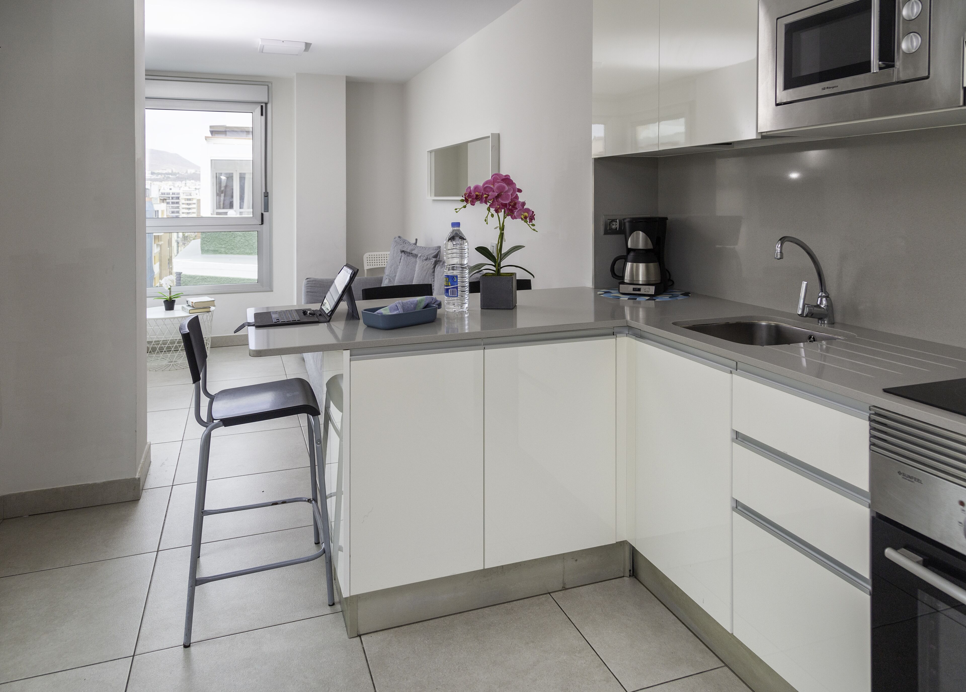 A modern kitchen with white cabinets, a stainless steel sink, and a built-in microwave.