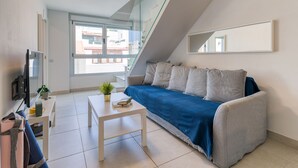 Un salon moderne avec un canapé, une table basse et un téléviseur.