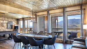 Amplia habitación con un techo de madera, una mesa de billar y vistas a montañas a través de amplios ventanales.