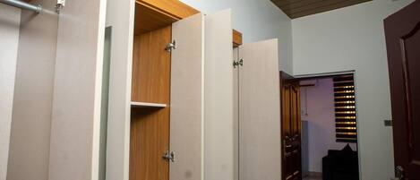 A hallway with a wooden door, a wardrobe with a mirror, and a black sofa in the background.