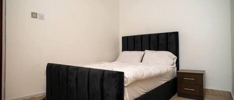 A bedroom with a bed, a nightstand, and a drawer unit.