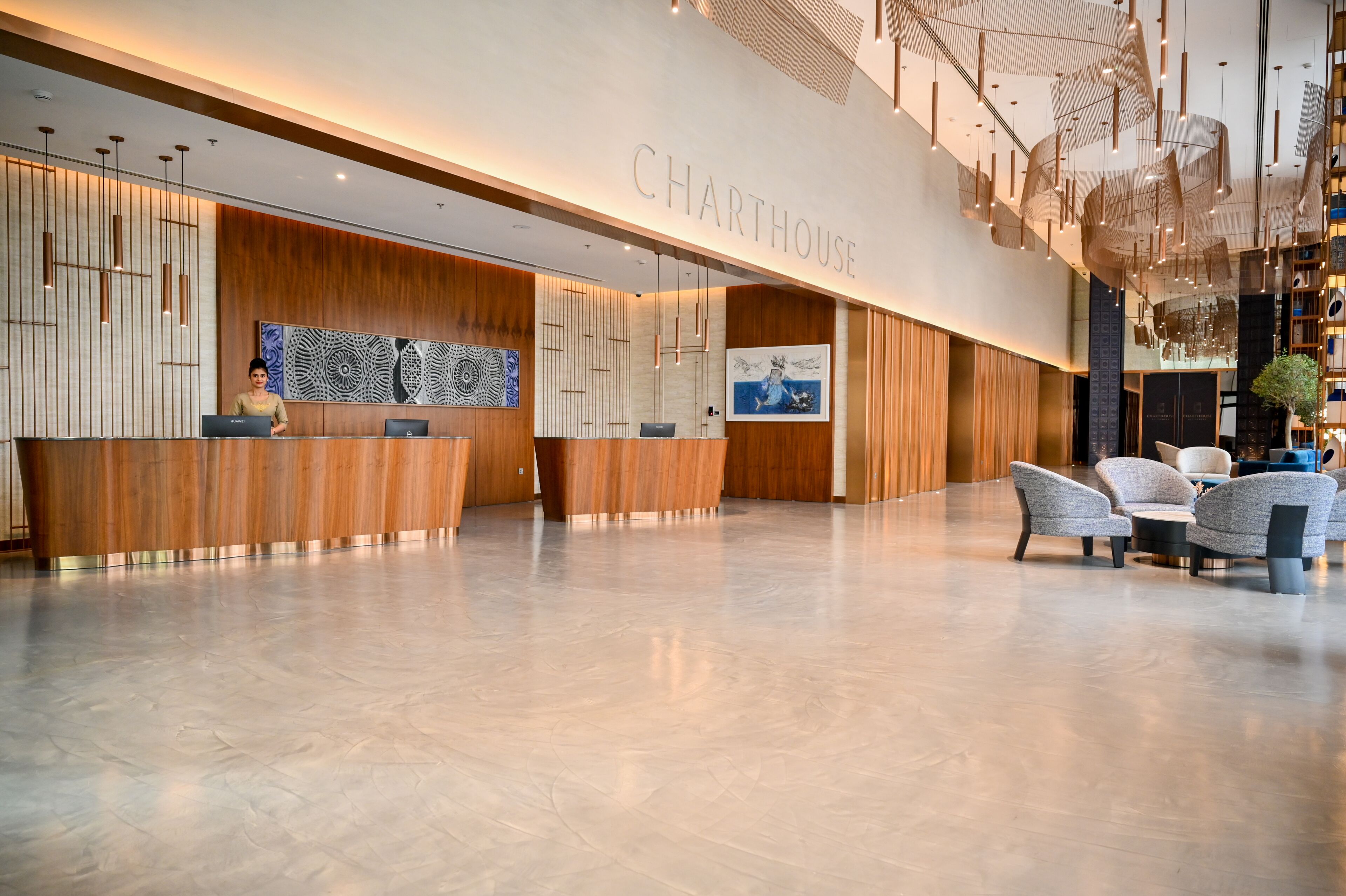 A modern hotel lobby with a reception desk, seating area, and a large artwork on the wall.