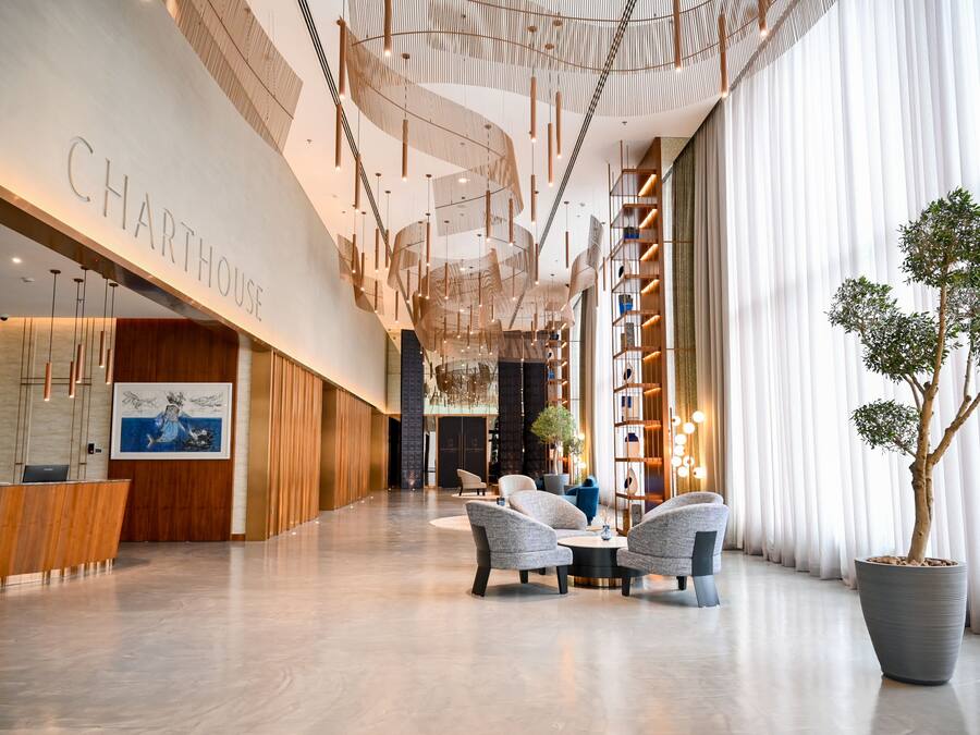 En moderne hotellobby med reception, siddepladser og et stort kunstudtræ.