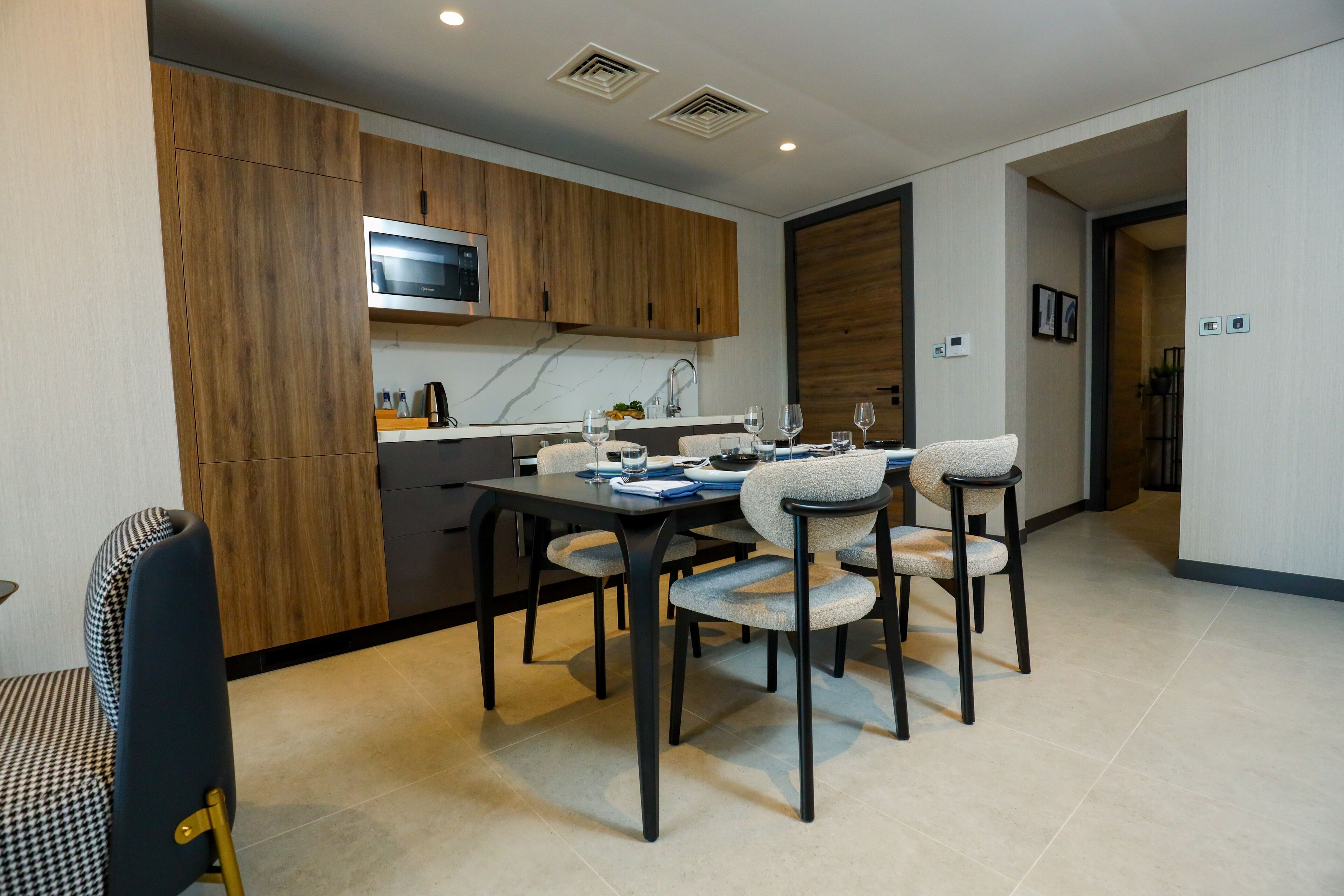 Una cocina moderna con armarios de madera, un microondas integrado y un comedor con cuatro sillas y una mesa para cuatro.