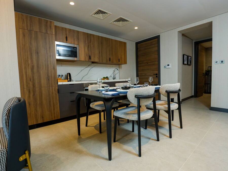 Una cocina moderna con armarios de madera, un microondas integrado y un comedor con cuatro sillas y una mesa para cuatro.