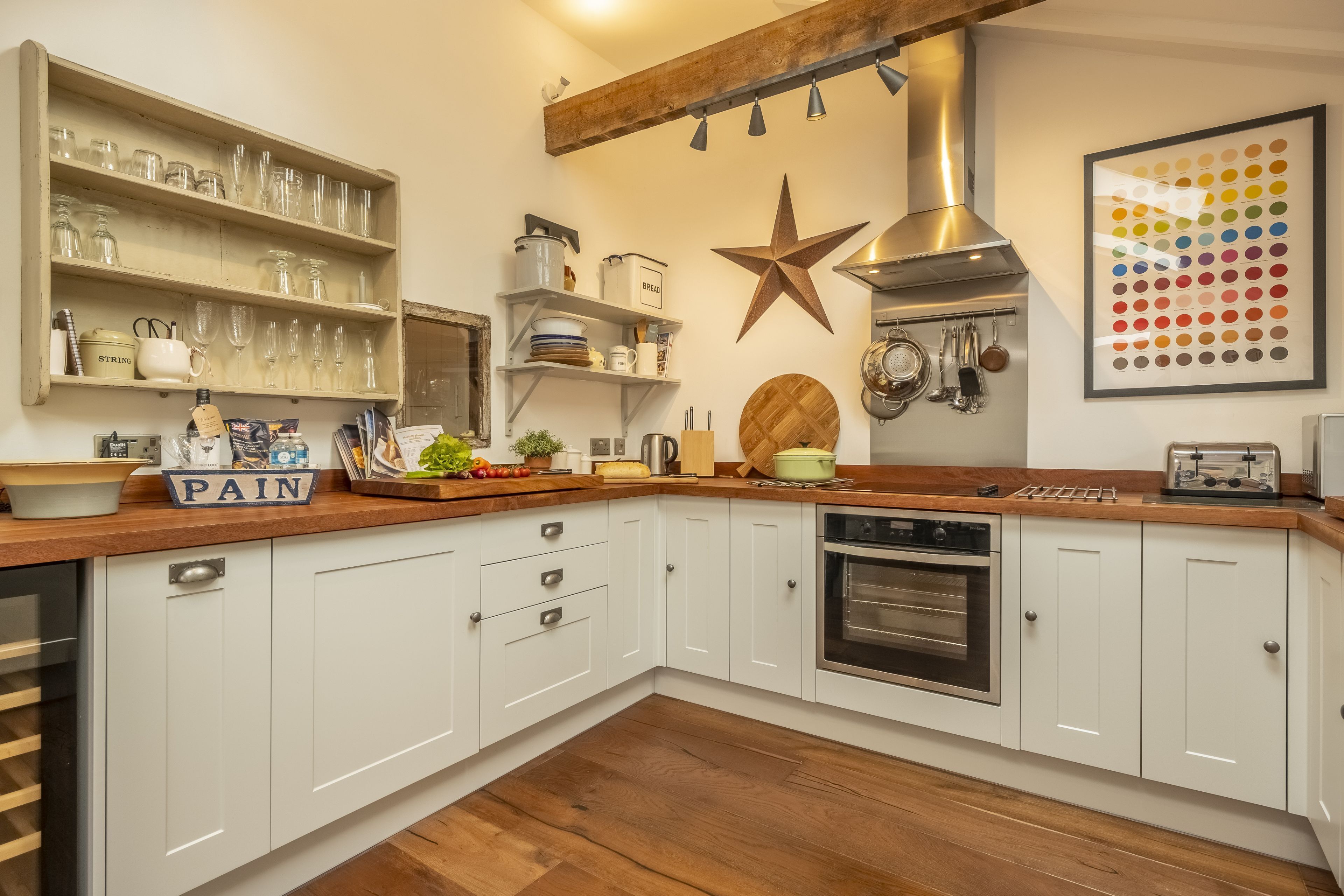 A kitchen with white cabinets, wooden countertops, a star decoration, and various kitchen utensils.