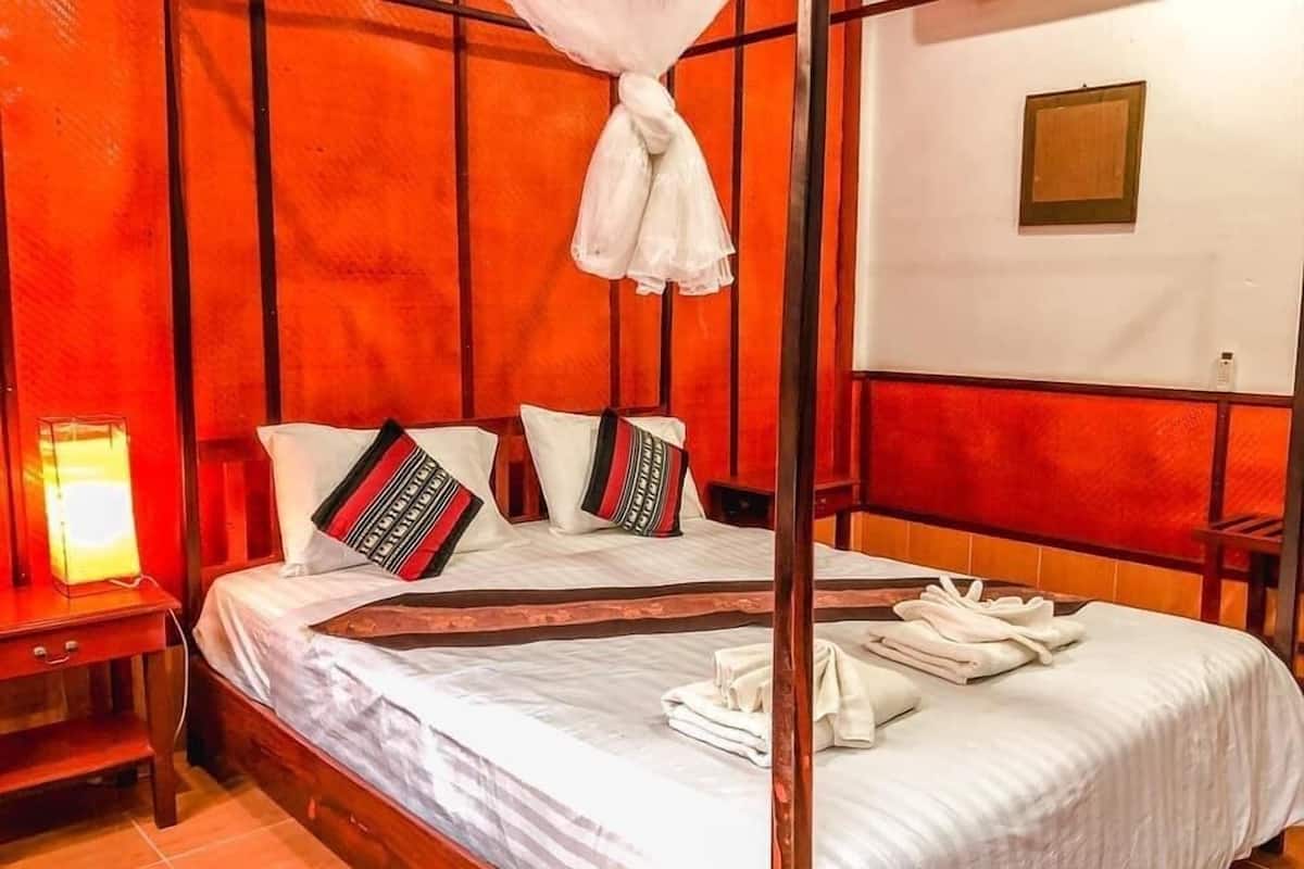 A room with a bed, pillows, a nightstand, and a wall-mounted light fixture.