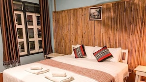 A neatly made bed with white linens and two pillows, a wooden headboard, and a small bedside table. - Jenda the views (Champasak)