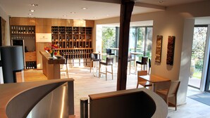 A modern interior with a wooden reception desk, a wine cellar, and a dining area with chairs and tables. - Ritterhof guest rooms at the Fitz-Ritter winery - VDP/Organic (Bad Dürkheim)