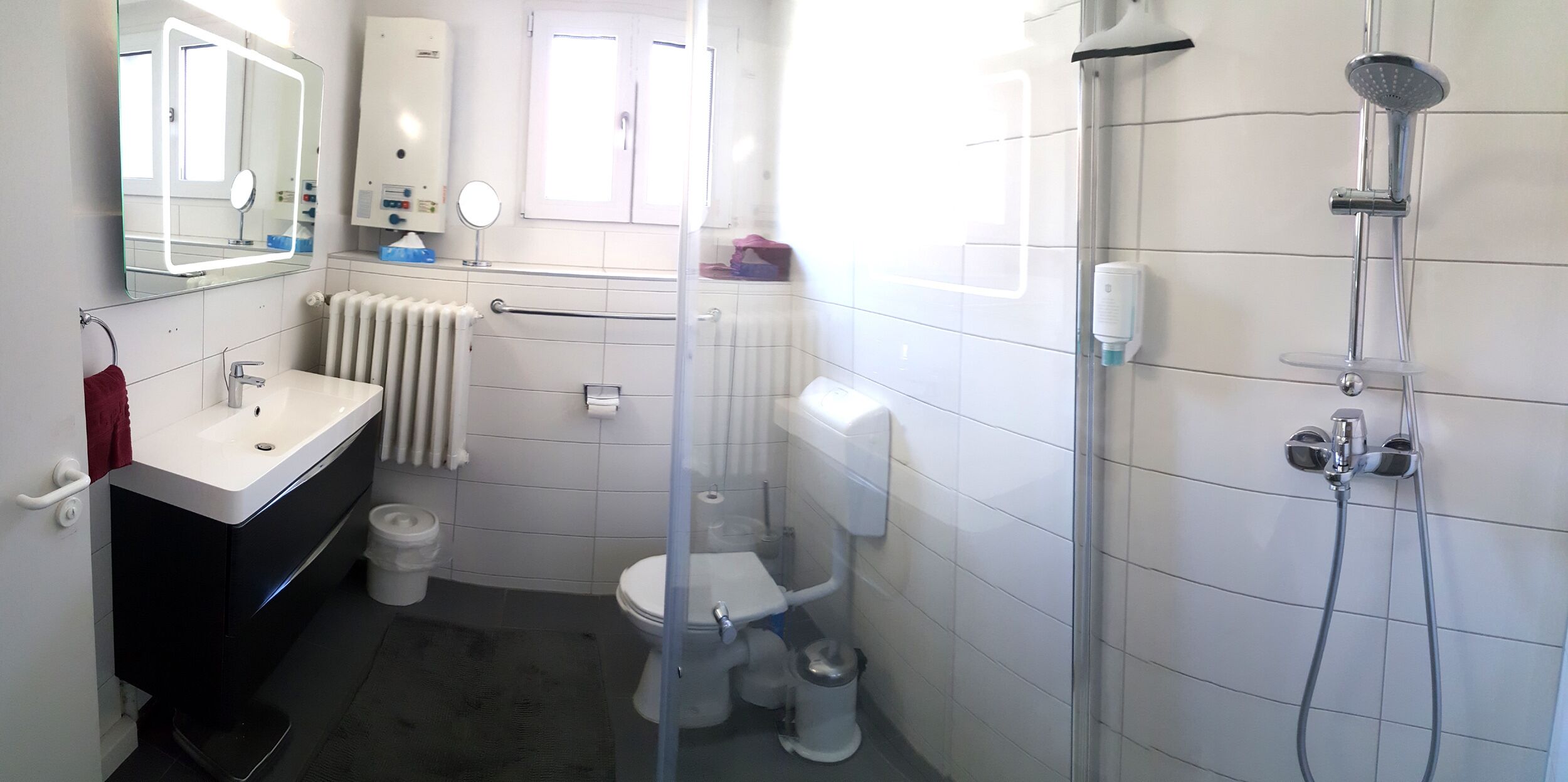 Une salle de bain moderne avec un lavabo blanc, un miroir, des toilettes et une douche.