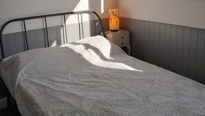 A bedroom with a bed, a nightstand, a lamp, a painting, and a window. - Perfect Chalet to Relax in k4 (Mablethorpe)