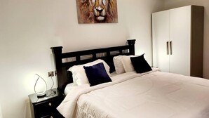 A bedroom with a bed, nightstands, a wardrobe, and a painting of a lion on the wall. - Luxurious & Comfy Gem-5 Star Location-pools, Gym! (Accra)