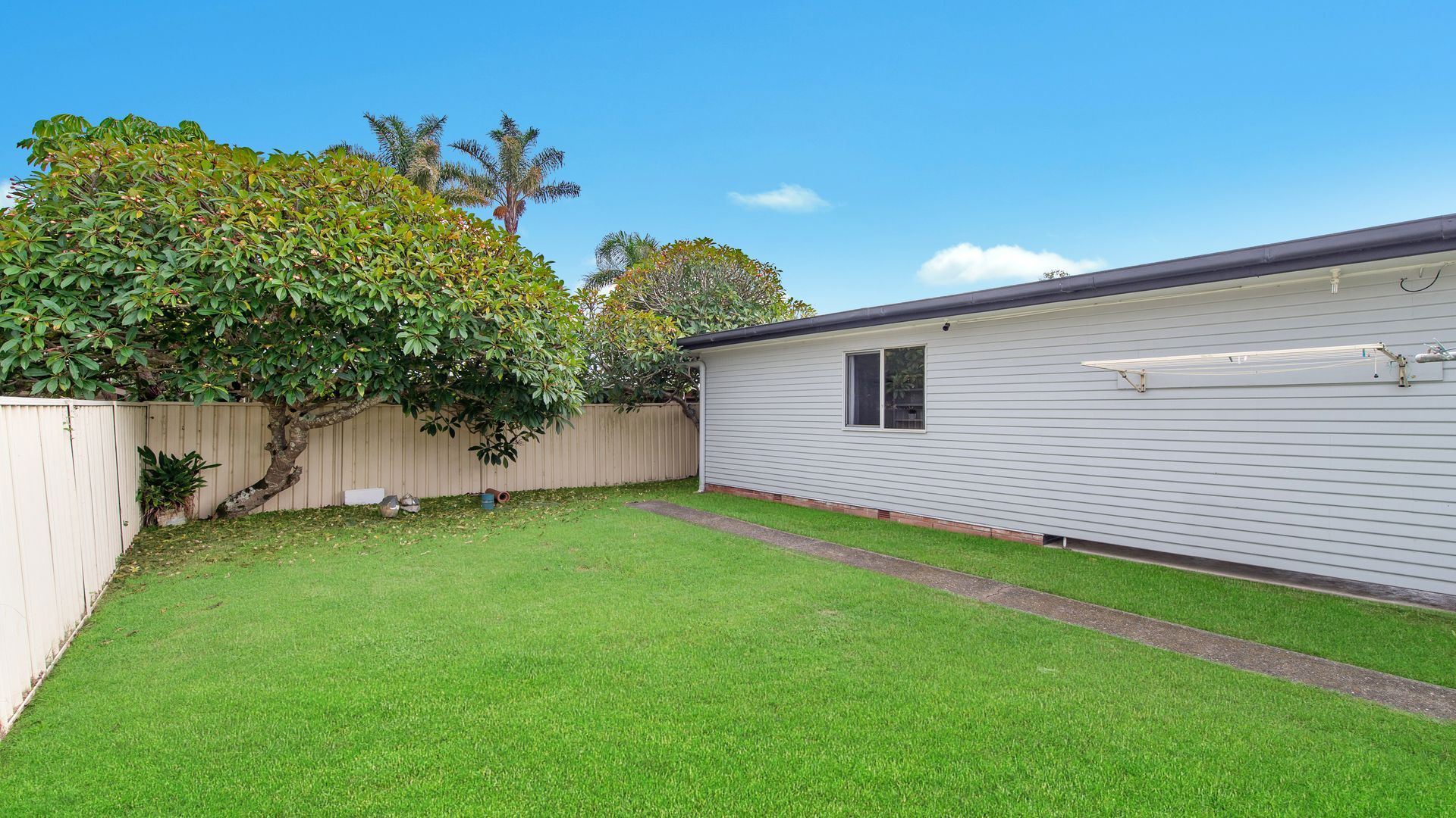 A single-story mobile home with a small front yard and a wooden fence.
