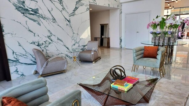 Un vestíbulo moderno con paredes de mármol, una mesa de centro de cristal y asientos contemporáneos.