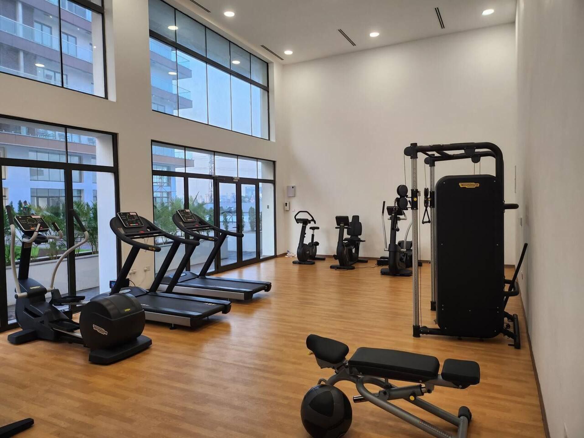 A spacious gym with treadmills, elliptical machines, a bench, and a squat rack.
