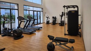 Un gimnasio amplio con cintas de correr, elípticas, una banca y una estructura para sentadillas.