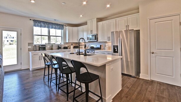 A modern kitchen with white cabinets, stainless steel appliances, and a central island with bar stools.