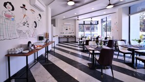 A modern restaurant with a black and white striped floor, dining tables with chairs, and a kitchen area in the background. - Apricsu Treeo Lonavala (Mawal)