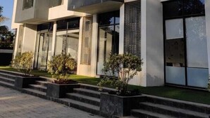 A modern multi-story building with balconies and large windows. - Apricsu Treeo Lonavala (Mawal)