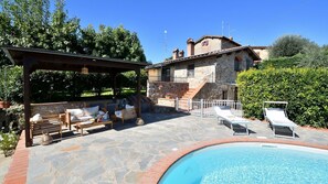 Ein Steinhaus mit Pool, Außenbereich mit Sitzgelegenheiten und einer überdachten Terrasse.