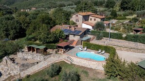 A villa with a swimming pool, stone architecture, and solar panels.