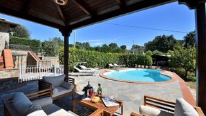 A covered outdoor area with a swimming pool, lounge chairs, and a table with drinks and snacks.