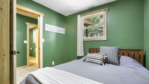 Ett sovrum med en säng, ett fönster, en dörr och en skylt på väggen.