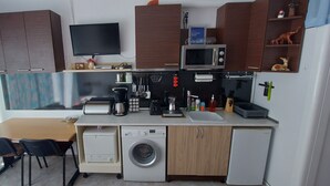 A compact kitchen with a microwave, toaster, sink, and a washing machine.