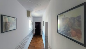 A hallway with wooden flooring, white walls, and framed artwork.