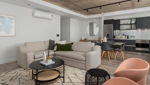 A modern living room with a sofa, coffee table, and chairs, a kitchen with a dining area, and a large mirror on the wall. - The Signature 307 (Cape Town)