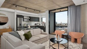 A modern living room with a sofa, a coffee table, and a view of a cityscape through large windows. - The Signature 307 (Cape Town)