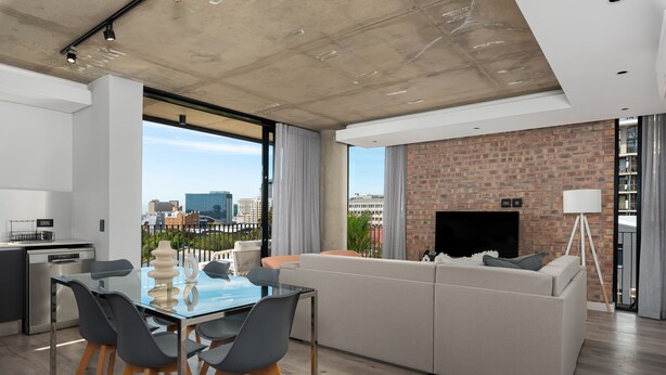 A modern living room with a glass dining table, grey chairs, a white sofa, and a brick fireplace. - The Signature 307 (Cape Town)
