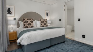 A modern bedroom with a large bed, a grey headboard, and two wall-mounted lamps. - The Signature 307 (Cape Town)