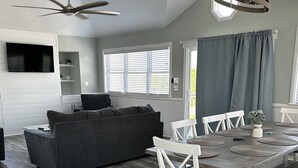 Une cuisine moderne avec un coin repas, des meubles blancs et un ventilateur de plafond.