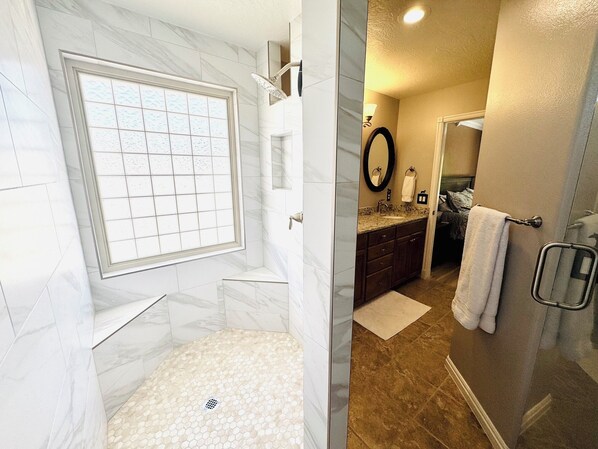 A bathroom with a shower, a sink, a mirror, and a towel rack.
