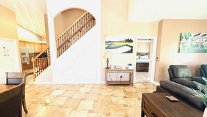 Ein geräumiger Wohnbereich mit Treppe, einem Esstisch, einer Couch und einer Küche im Hintergrund.