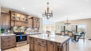 A spacious kitchen with wooden cabinets, a large island, and a dining area with a view.