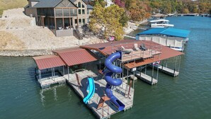 A waterfront property with a water slide, docked boats, and a building with balconies.