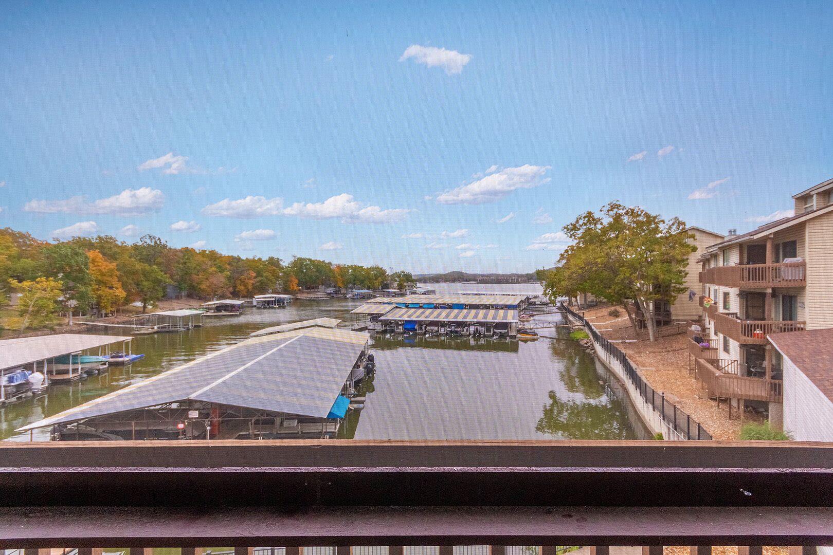 A marina with docked boats, a covered boat launch ramp, and a building with a balcony.