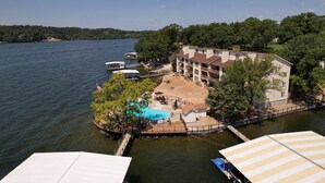 A lakeside property with a swimming pool, dock, and a building with multiple balconies. - Lakefront Couple Retreat near Hot Spots and Dining (Lake Ozark)