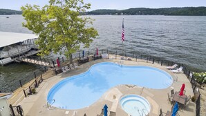 A swimming pool with a deck, lounge chairs, and a flag. - Lakefront Couple Retreat near Hot Spots and Dining (Lake Ozark)