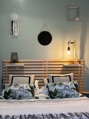 A bedroom with a wooden slat headboard, a round mirror, a dreamcatcher, and a bedside lamp. - ROYAN, Room with a Private Terrace (Royan)