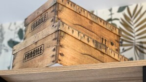 Une caisse en bois portant l’étiquette « FRAGILE » est posée sur une étagère.